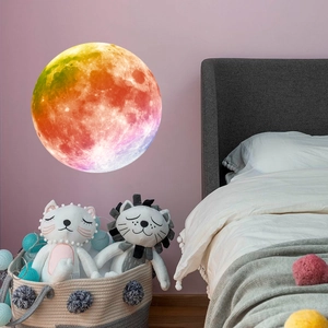 Glow-in-the-dark rainbow moon wall sticker with crater texture in a cozy bedroom setting