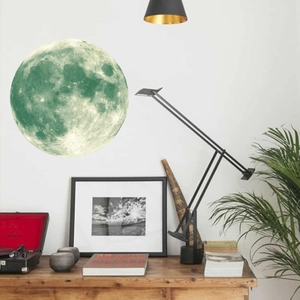 Detailed view of a glowing green moon wall sticker on a white wall in a cozy room