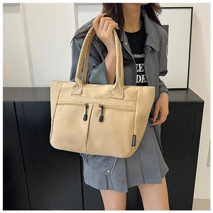 Detail view of a beige nylon tote bag with dual front zippers and sturdy handles
