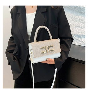 Detail of white leather handbag with champagne sequins and large gold EE metal logo