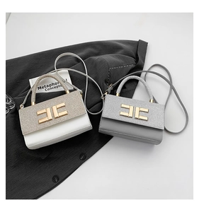Close-up of glitter flap and golden metal logo on stylish two-tone commuter bag