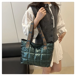 Dark green quilted tote bag with ethnic pattern straps worn on shoulder by model