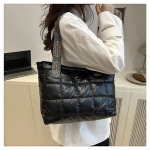 Detail of black quilted tote bag featuring vibrant geometric pattern straps and glossy finish