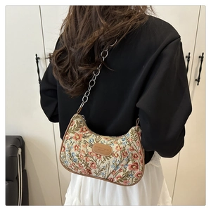 Close-up of floral jacquard crescent bag with leather trim and silver chain strap detail