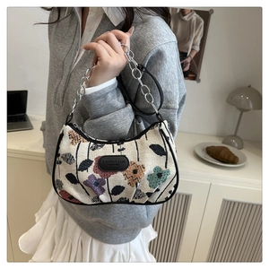 Close-up of floral crescent bag with silver chain strap and vintage pattern detail