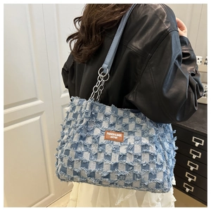 Détail du sac cabas en denim à damier bleu avec bords effilochés et bandoulière en cuir