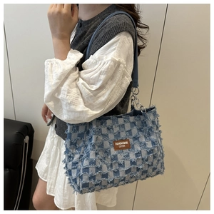 Détail du sac cabas en jean à carreaux bleus et blancs avec bords effilochés et cuir