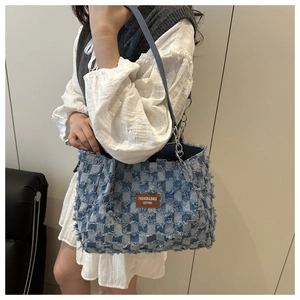 Détail du sac fourre-tout en denim à damier bleu avec bords effilochés et étiquette