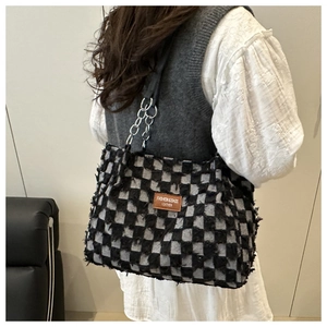 Détail du sac cabas à carreaux avec bords effilochés et bandoulière en chaîne et cuir