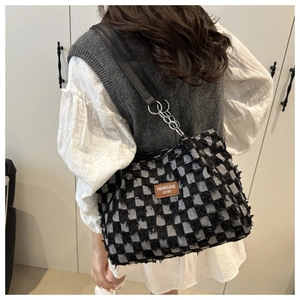 Détail du sac cabas à carreaux avec tissu texturé et écusson logo en cuir