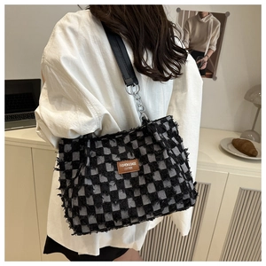Détail du sac cabas en denim à carreaux avec tissu effiloché et étiquette en cuir brun