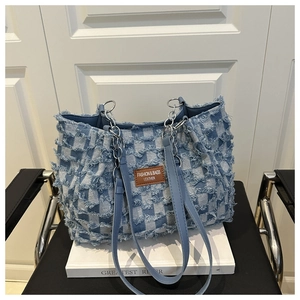 Détail du cabas en jean à damier avec écusson en cuir et attaches en chaîne argentée