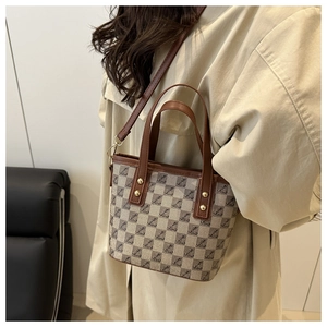 Close-up of monogram print tote bag with brown leather handles and gold rivet details