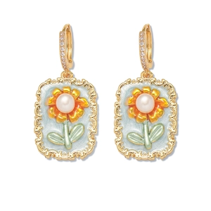 Détail de boucles d'oreilles vintage avec émail bleu, tournesol et perles d'eau douce