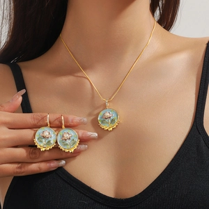 Detail of floral enamel jewelry set featuring pink lotus and pearls on light blue base