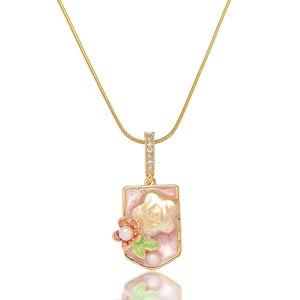 Détail du pendentif perle baroque avec émail rose et reliefs floraux sur chaîne dorée
