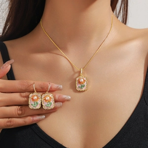 Détail d'un ensemble collier et boucles d'oreilles fleuris en émail avec perles