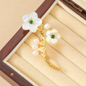 Détail de la broche fleur en nacre avec pierres vertes et perles sur support velours