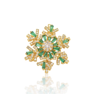 Macro shot of snowflake brooch with emerald green baguette gems and clear cubic zirconia