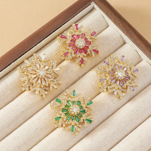 Rotating snowflake zircon brooches in white, red, purple, and green on wood display