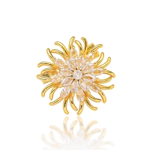 Broche fleur dorée avec cristaux de marquise blancs sur fond blanc avec reflet