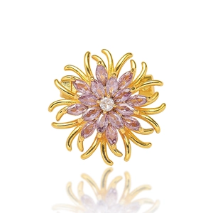 Détail d'une broche marguerite dorée sertie de cristaux roses et d'un diamant blanc