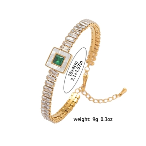 Detailed view of a gold tennis bracelet with emerald square gem and shell inlay
