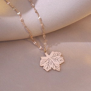 Elegant rose gold leaf pendant necklace displayed on a textured champagne satin cloth