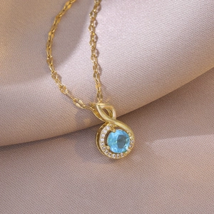 Elegant gold titanium necklace with blue cubic zirconia note pendant on silk background