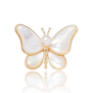 Macro shot of butterfly brooch with white mother-of-pearl wings and central pearl inlay