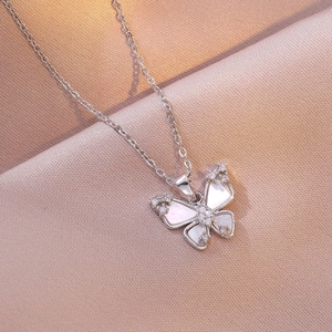 Collier papillon élégant avec zircon et nacre blanche sur un fond de soie violette