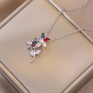 Collier pendentif fleur avec zircons colorés sur une boîte à bijoux champagne