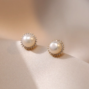 Elegant freshwater pearl stud earrings with sunburst zircon halo on beige silk fabric