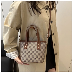 Canvas tote bag with leather trim worn by a model in a beige trench coat for a chic look