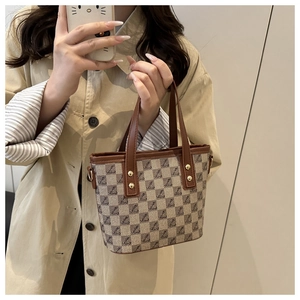 Detail of vintage checkered tote bag with brown leather handles and monogram print