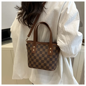 Detail shot of the brown checkered crossbody bucket bag with leather strap and metal studs