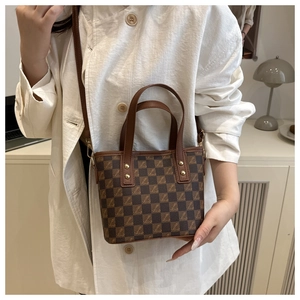 Detail of vintage checkered bucket bag with gold rivets and adjustable leather straps