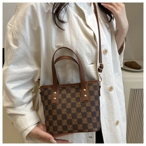 Brown checkered tote bag with double handles and golden hardware shown in a lifestyle setting
