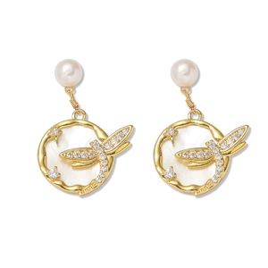 Détail de boucles d'oreilles libellule dorées avec perles baroques et nacre