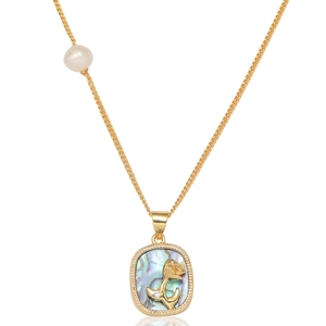 Détail du pendentif queue de dauphin doré avec nacre irisée et perle blanche élégante