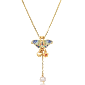 Detail of gold butterfly enamel pendant with a white pearl and red gemstone charm