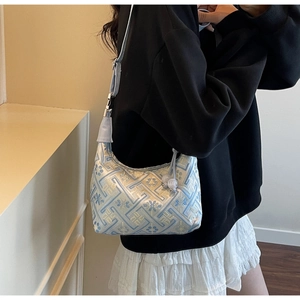 Détail du sac hobo brodé bleu clair avec motifs géométriques et bandoulière en cuir