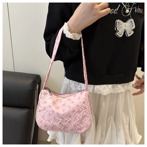 Close-up of pink shoulder bag featuring an embossed bow pattern and metal zipper detail