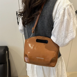 Glossy brown patent leather shoulder bag with cutout handle and adjustable strap