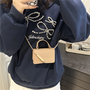 Chic beige mini crossbody bag with gold buckle shown on a model in casual navy sweatshirt