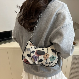 Retro knit floral crescent underarm bag with metal chain strap worn by a model