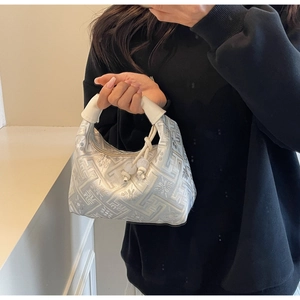 Détail du sac à main argenté à motif géométrique avec poignée en cuir blanc et perle