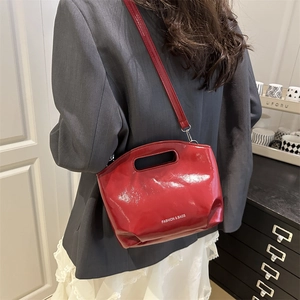 Glossy red crossbody bag with Fashion & Bags text shown on a model with a grey blazer
