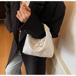 Détails d'un sac à main blanc élégant avec texture florale et pompon à perles