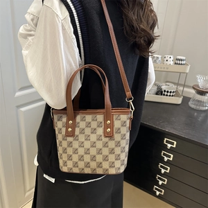 Retro monogram bucket tote bag with leather handles and detachable strap in a home setting